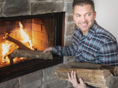 Man putting woods log in the fireplace
